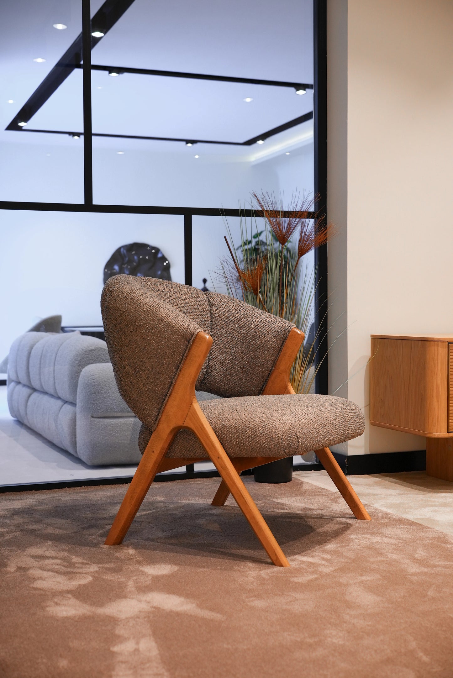 Side profile of Lia armchair showing elegant wooden legs and soft fabric