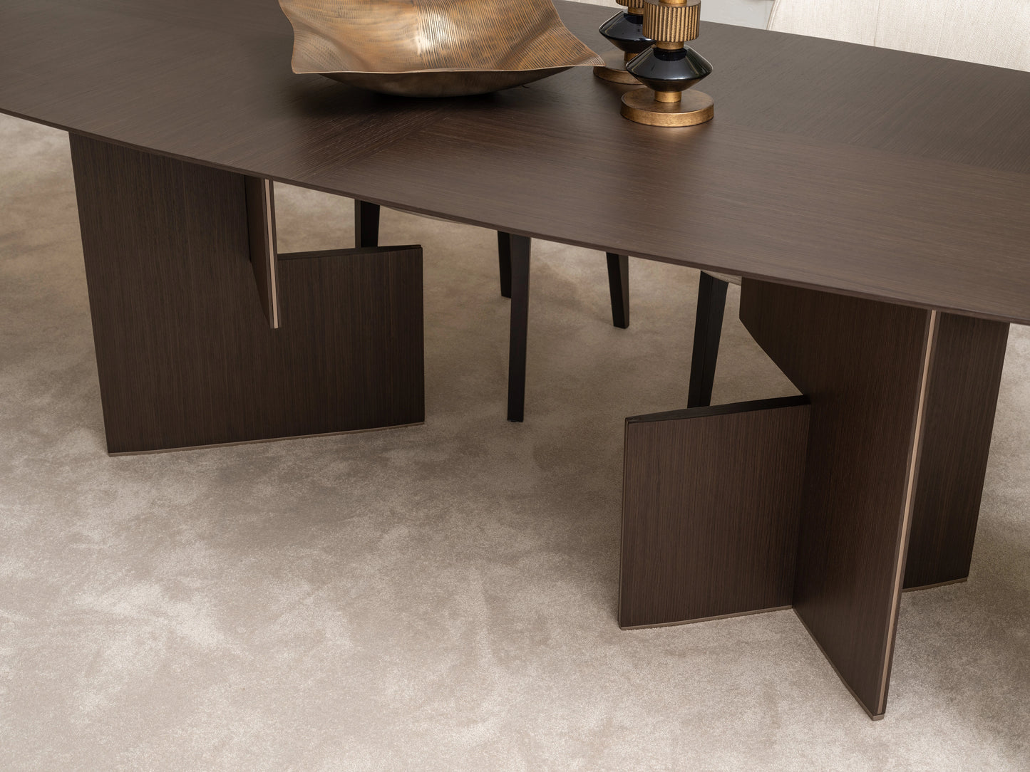 Close-up of Moka dining table base with dark wood veneer and gold decorative bowl
