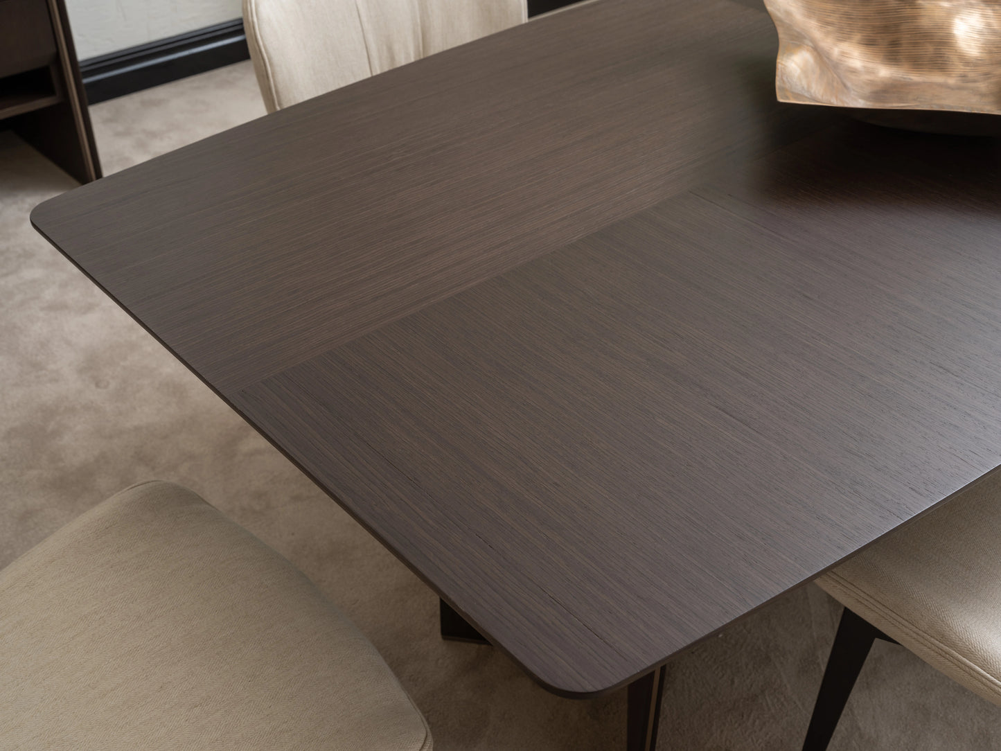 Close-up of Moka dining table surface in dark wood veneer with gold centrepiece