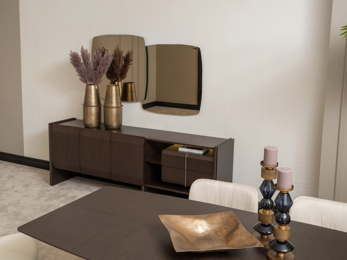 Moka sideboard with gold vases and modern mirror behind dark wood dining table