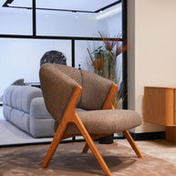 Side profile of Lia armchair showing elegant wooden legs and soft fabric