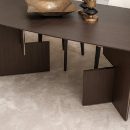 Close-up of Moka dining table base with dark wood veneer and gold decorative bowl