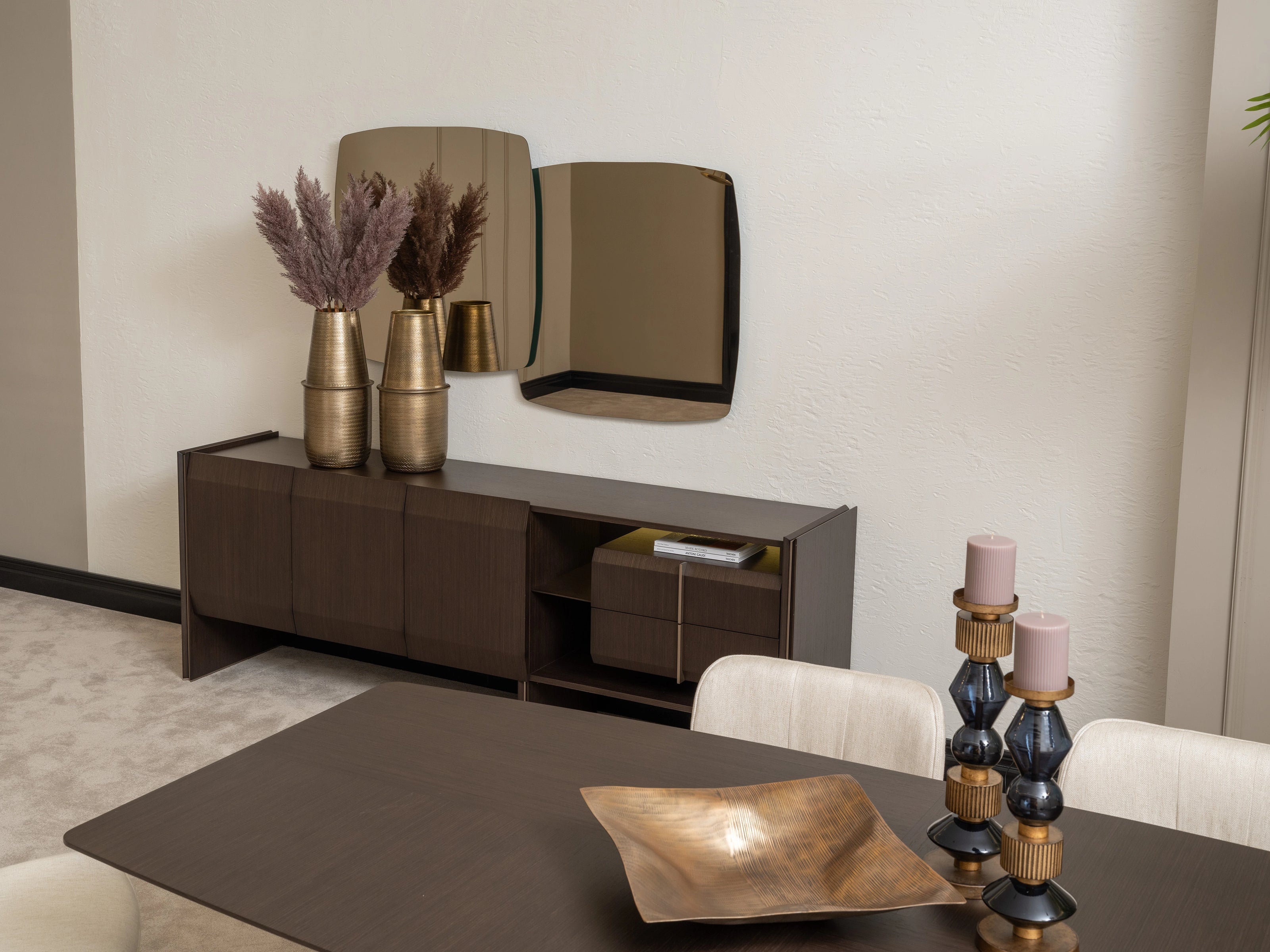 Moka sideboard with gold vases and modern mirror behind dark wood dining table